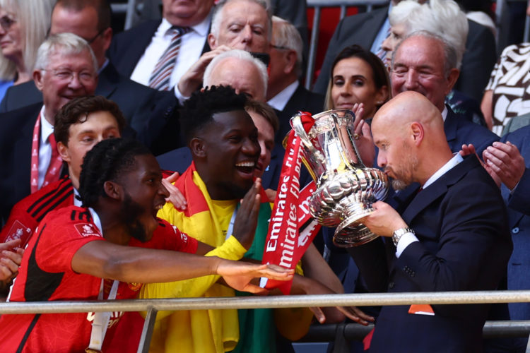 Manchester United manager Erik Ten Hag kisses the trophy as Andre Onana and Willy Kambwala following during the Emirates FA Cup Final match between...