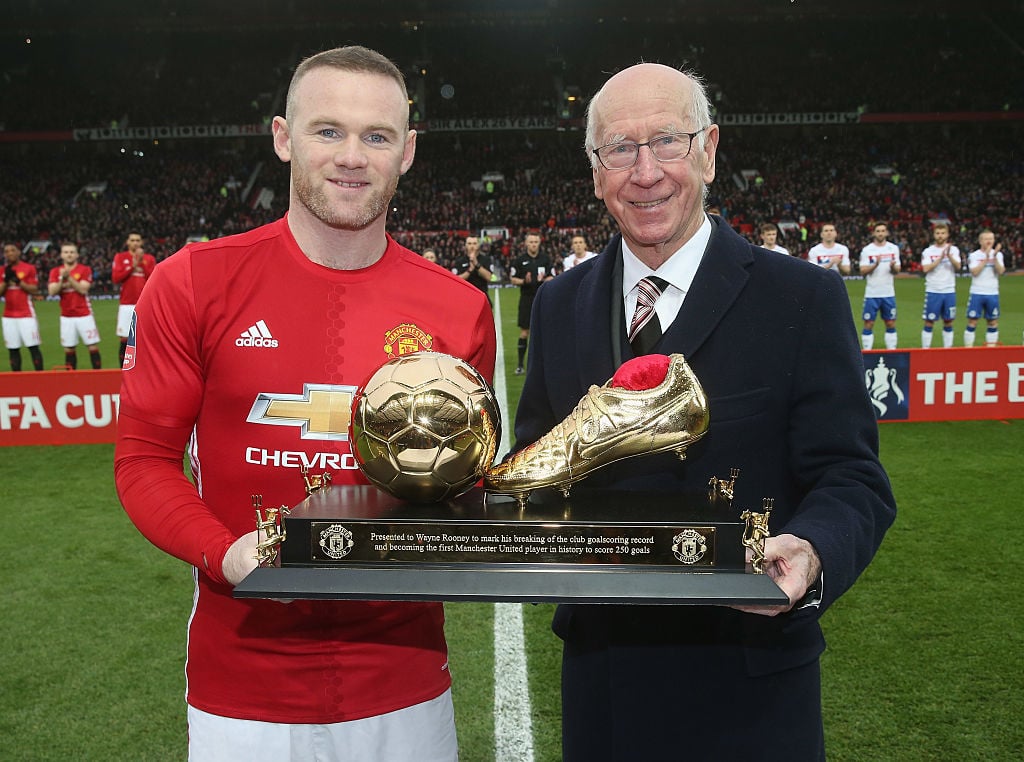 Wayne Rooney of Manchester United is presented with a golden boot by Sir Bobby Charlton to mark his 250th Manchester United goal, which saw him bre...