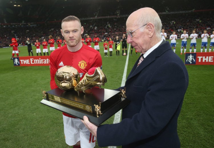 Wayne Rooney of Manchester United is presented with a golden boot by Sir Bobby Charlton to mark his 250th Manchester United goal, which saw him bre...